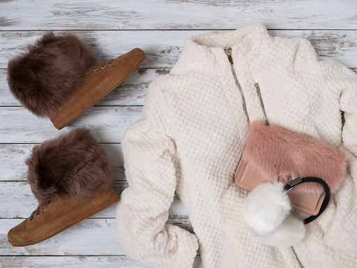 mixing textures of brown suede boots with a white bouclé jacket, pink fur bag and ear muffs