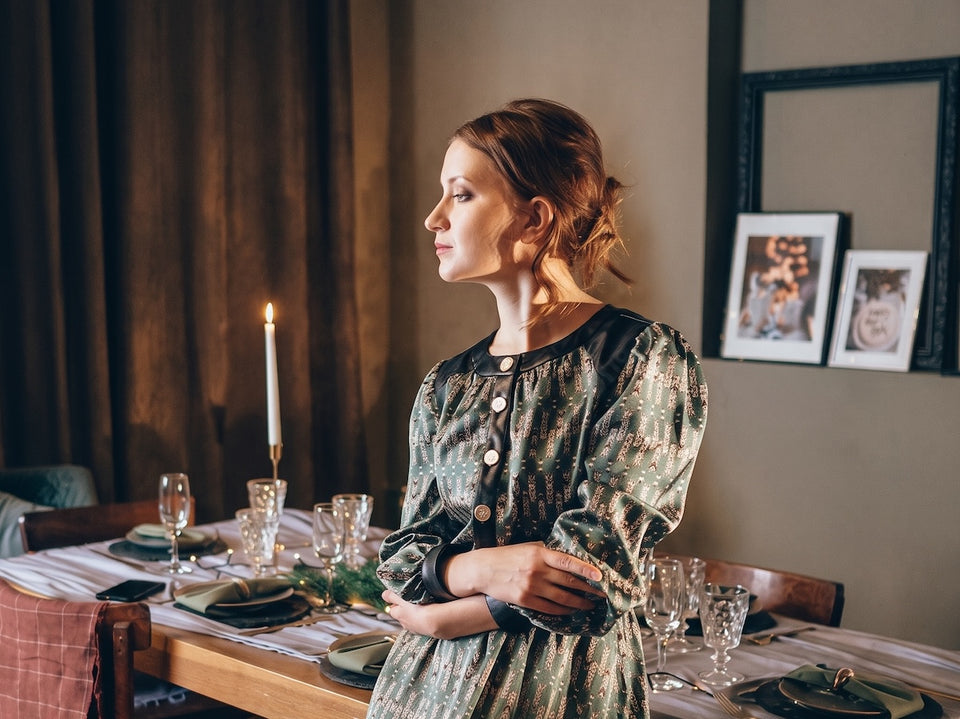 a woman in a patterned button front silk dress leaning on her table which is ready for a dinner party