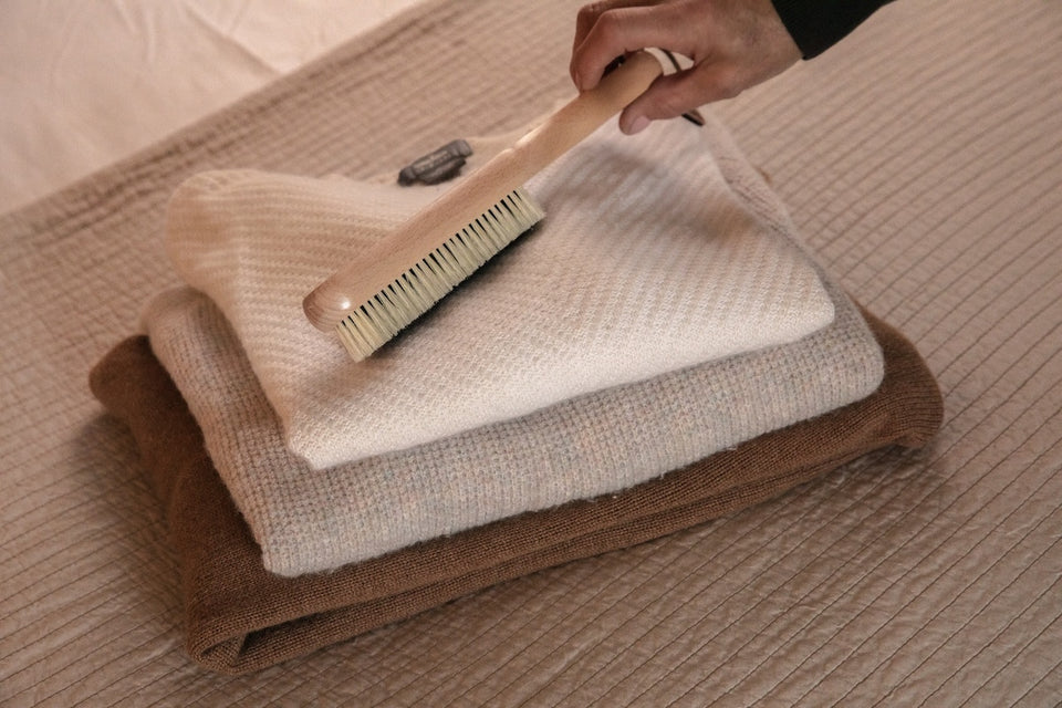 a clothes brush on a pile of winter knits