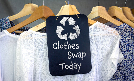 pretty tops on hangers and a ‘Clothes Swap Today’ sign with the recycle symbol