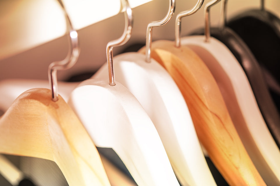 a close up of a row of natural, white and dark wooden hangers