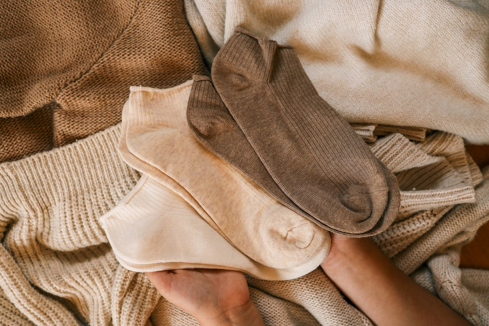 a few pairs of socks and woollen knits in shades of cream and brown