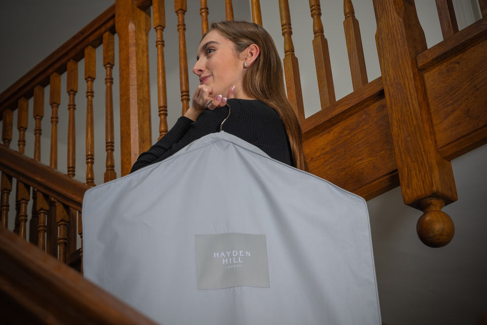 a woman standing on a staircase carrying a grey Hayden Hill organic hanging bag