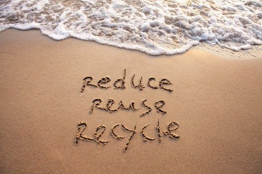 the message Reduce Reuse Recycle written into the sand on the beach