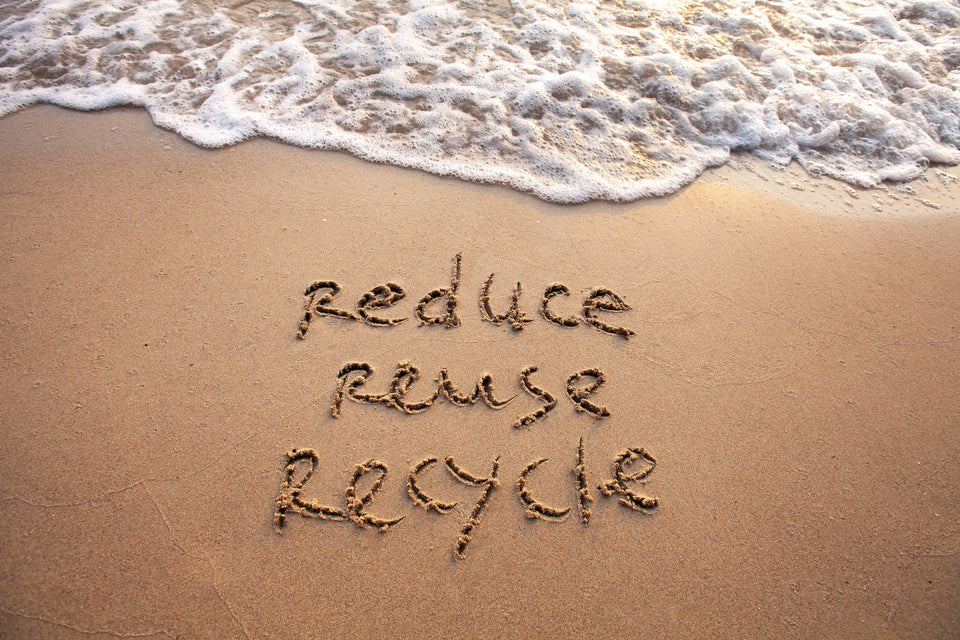 the message Reduce Reuse Recycle written into the sand on the beach