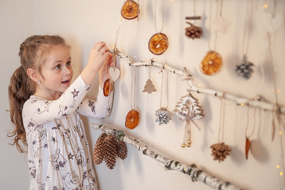 a young girl adding dried orange slices to her sustainable christmas wall hanging